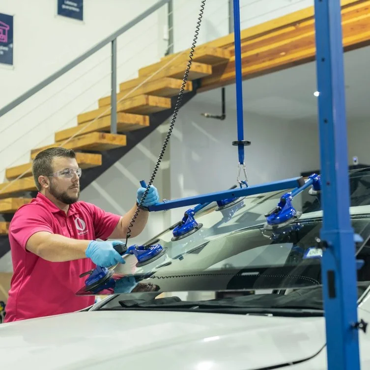 Optic-Kleer technician setting a new windshield with suction lifting tools
